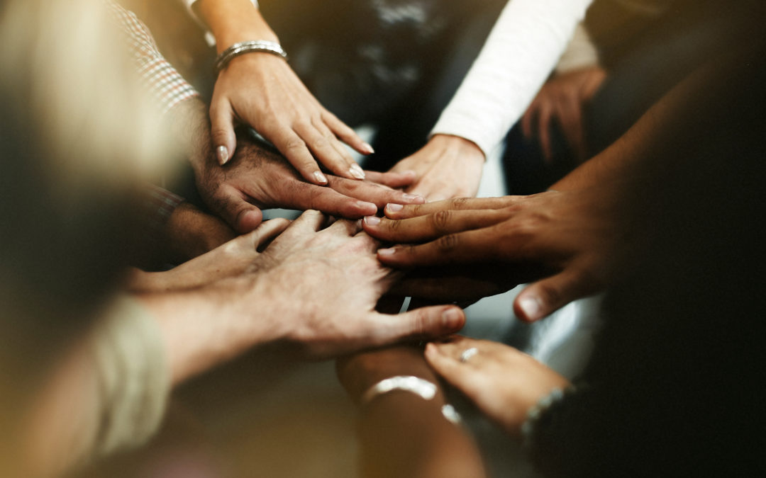 A diverse team putting their hands together.