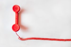 A red corded phone on a white background.